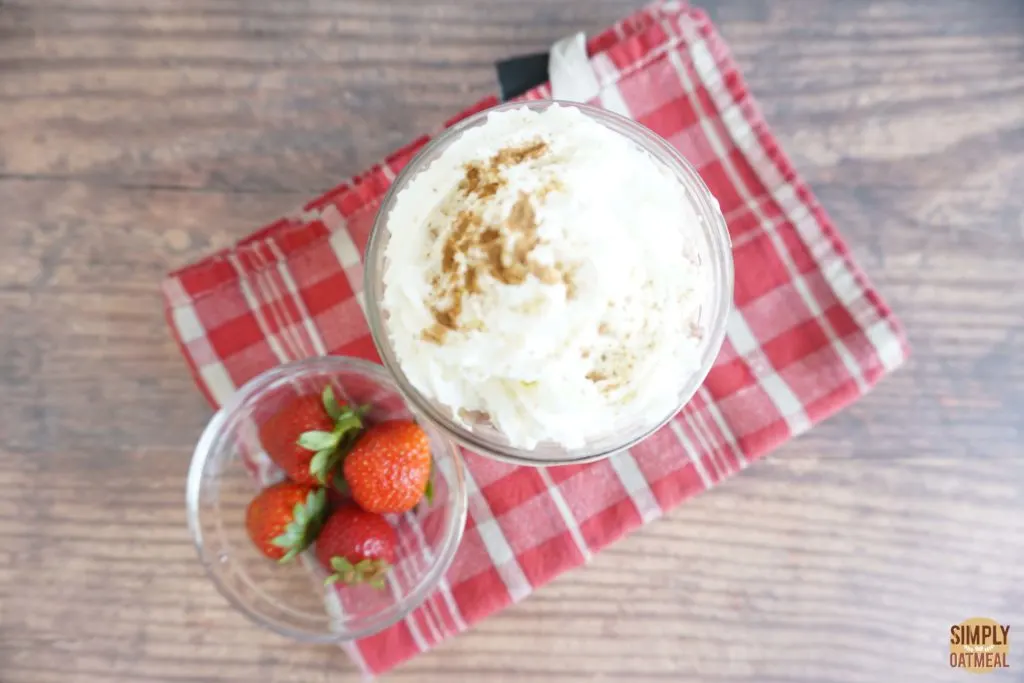 Serving of strawberry and cream overnight oats in a glass cup Serving of strawberry and cream overnight oats in a glass cup topped with fresh whipped cream sprinkled with cinnamon