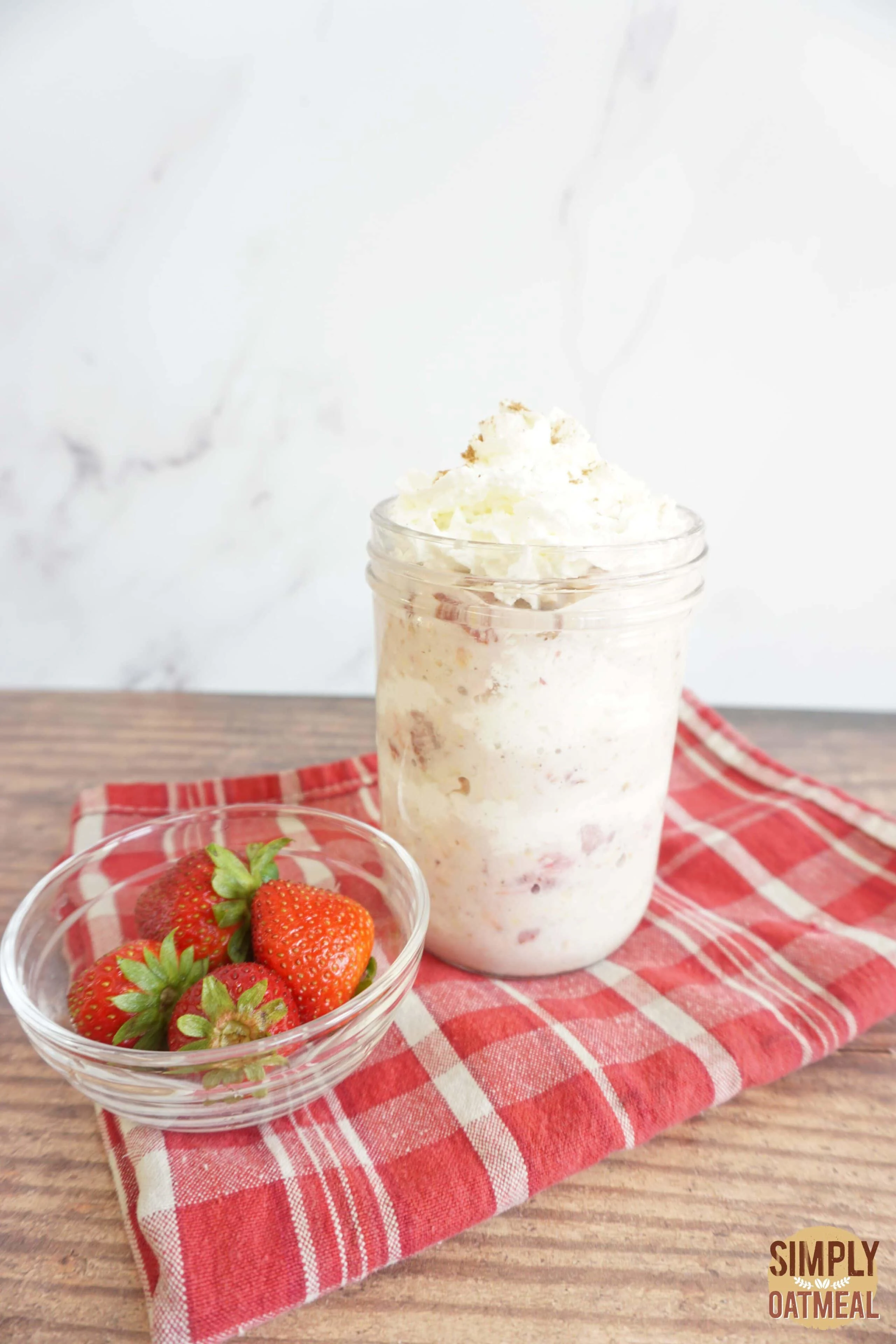 Strawberry and cream overnight oats in a mason jar with whipped cream and wild strawberries.