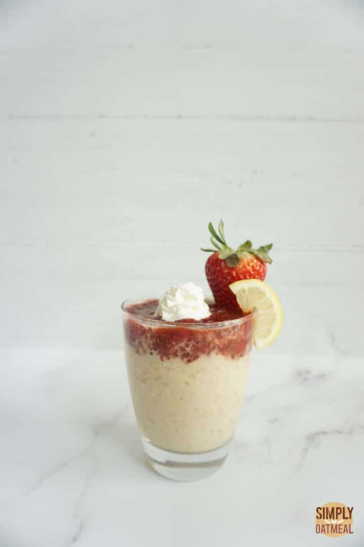 Single serving of strawberry lemonade overnight oats in a glass cup with strawberry chia jam on top