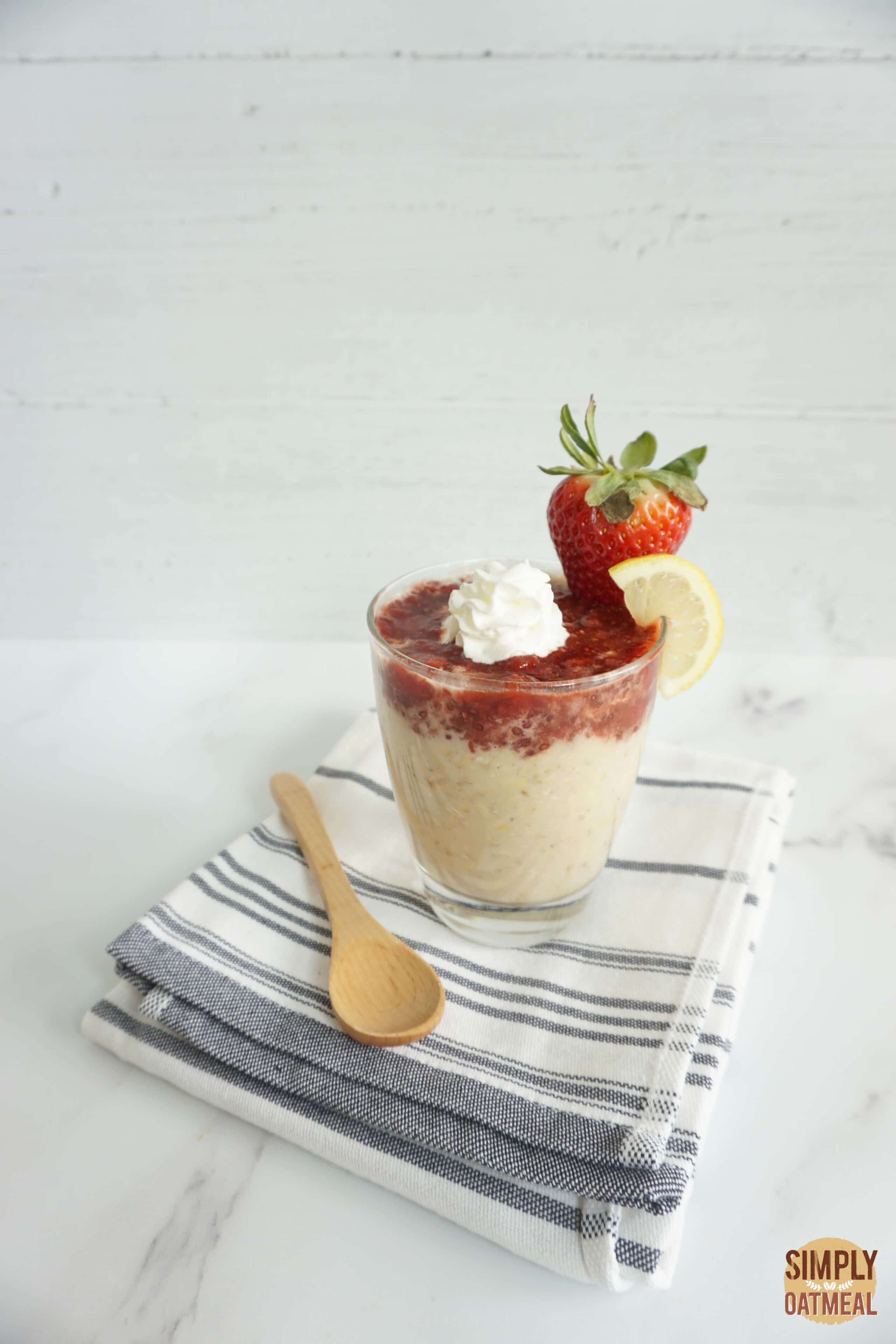 Serving of strawberry lemonade overnight oats in a glass cup with strawberry chia jam and lemon zest on top