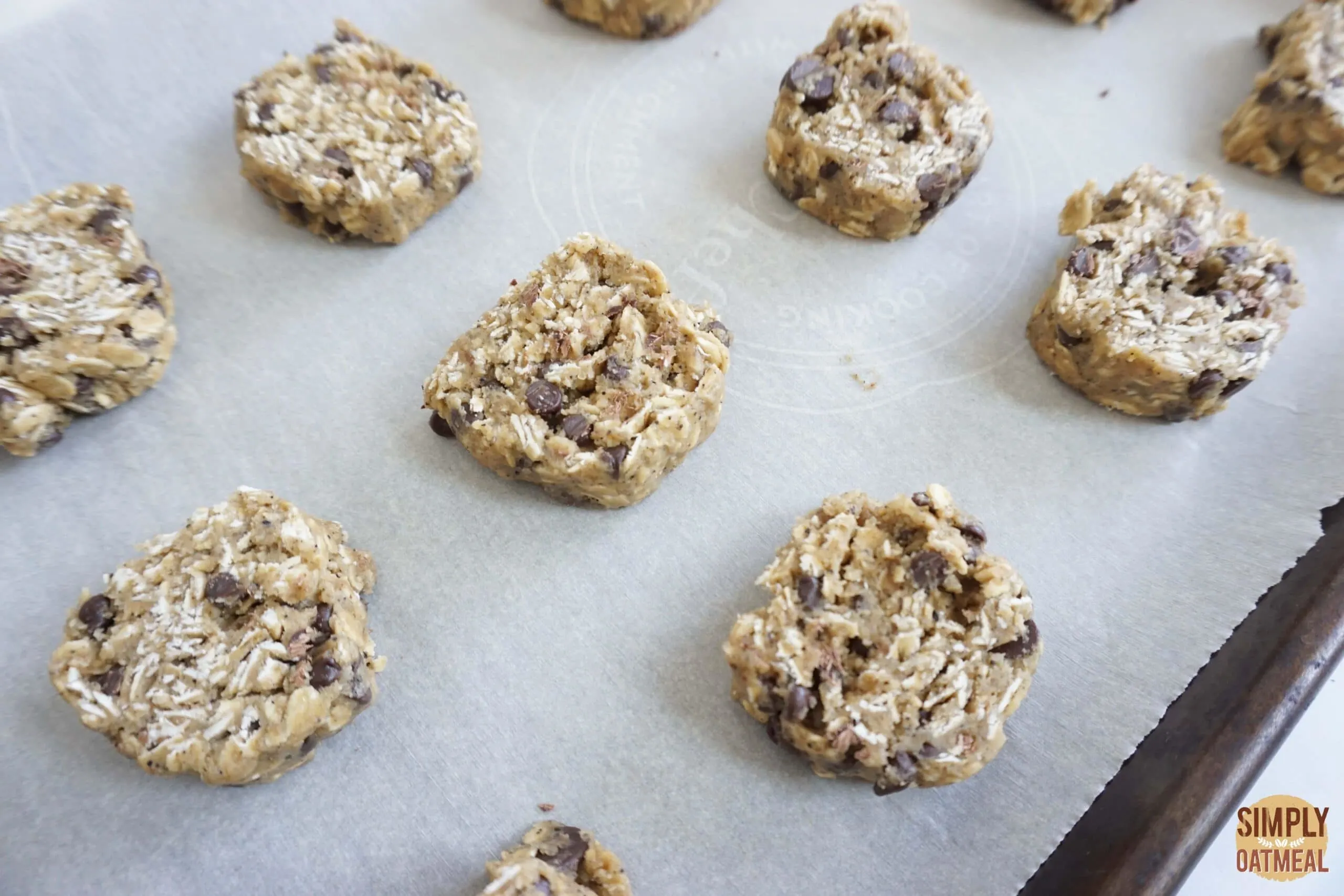 Raw espresso chocolate chip oatmeal cookies on a parchment paper lined baking sheet