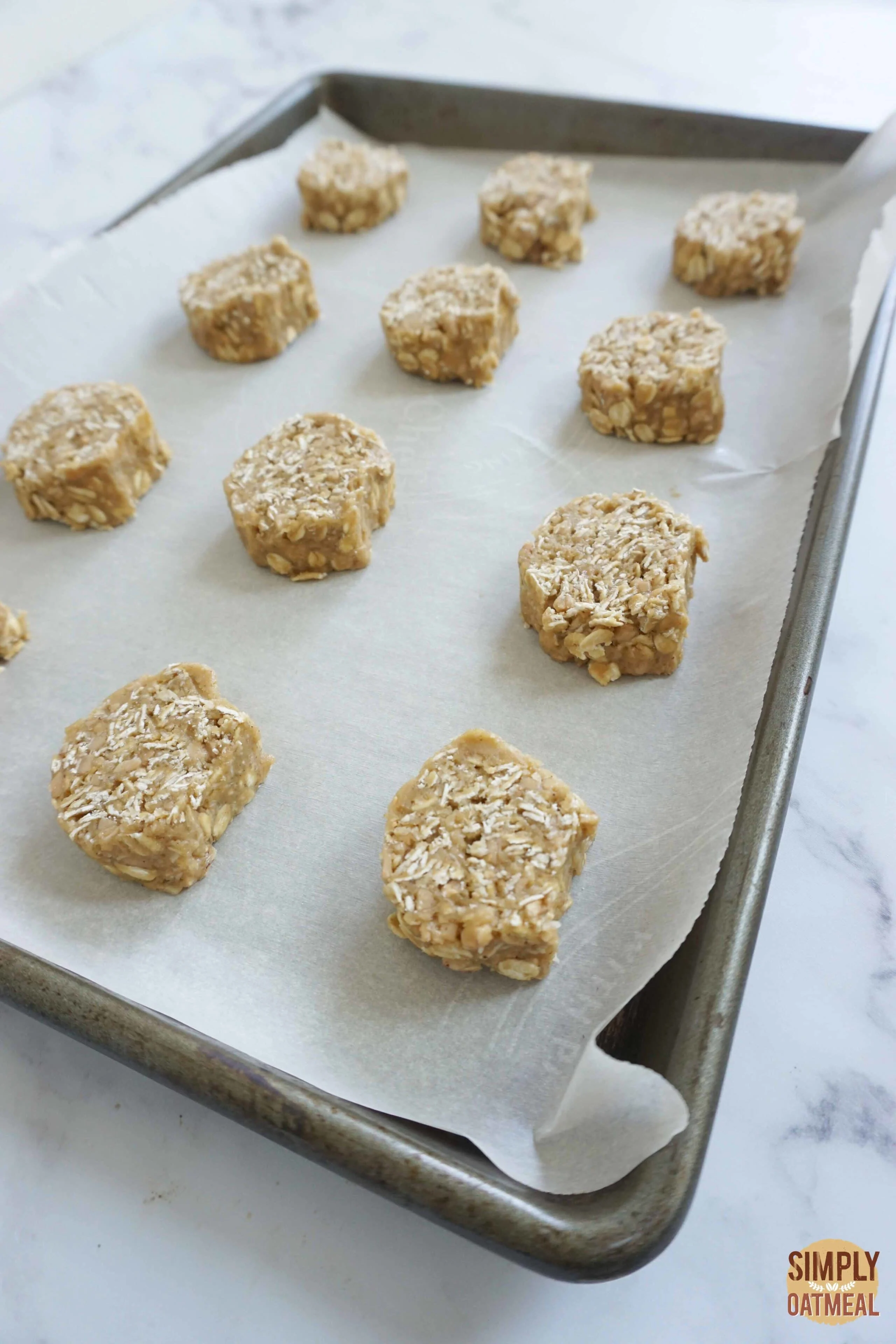 Raw toffee coconut oatmeal cookies on a parchment paper lined baking sheet