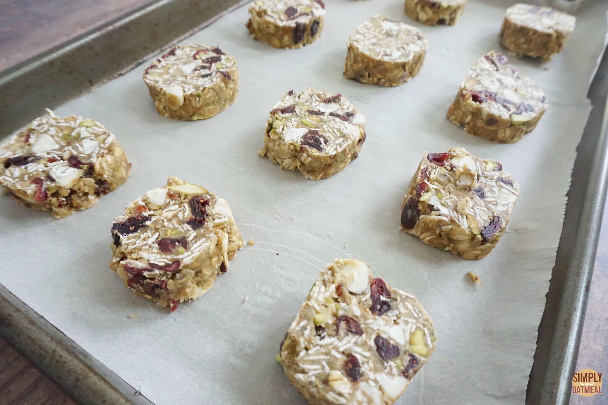 Raw white chocolate cherry oatmeal cookies on a parchment paper lined baking sheet