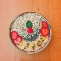 Bowl of oatmeal topped with superfood weight loss ingredients like banana, berries, chia seeds and cocoa nibs.