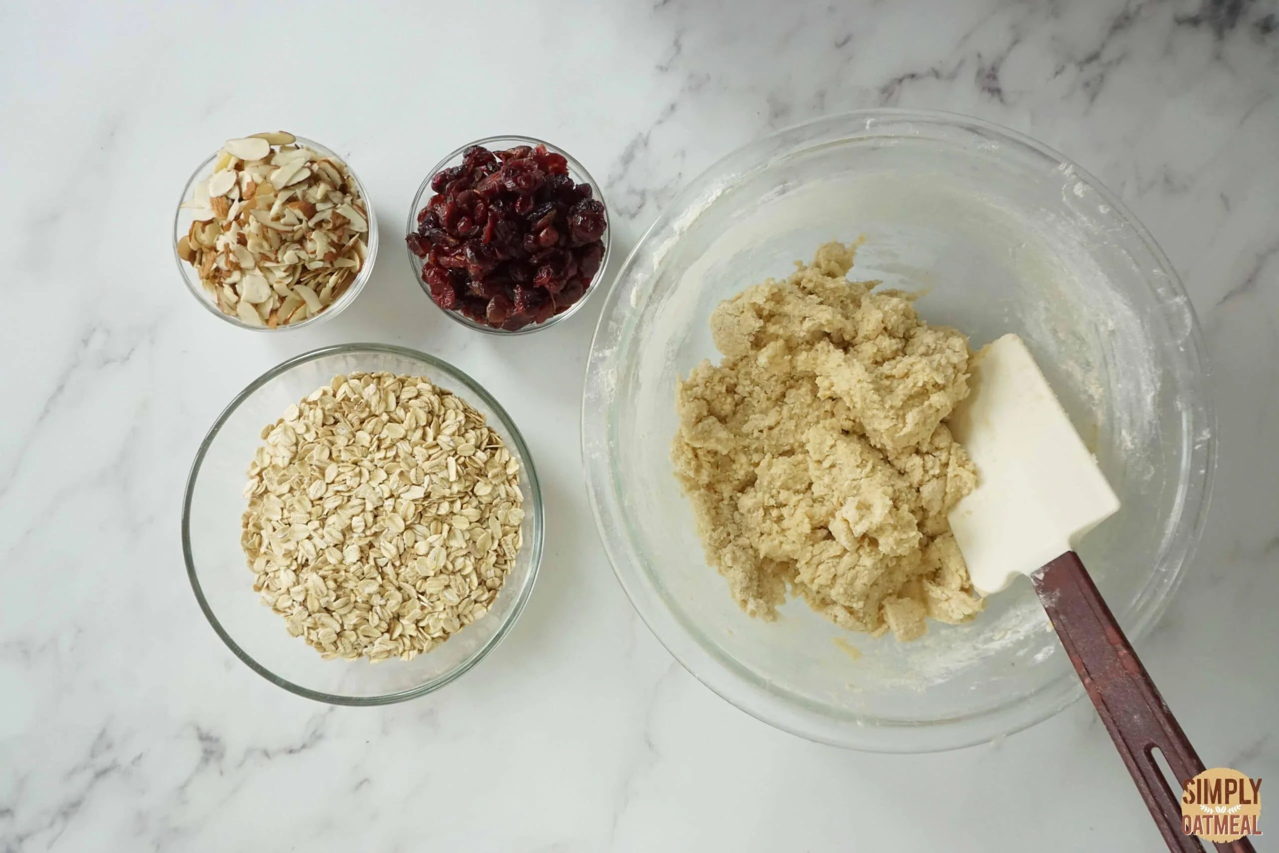 Fold dried cranberries and almonds into oatmeal cookie dough.