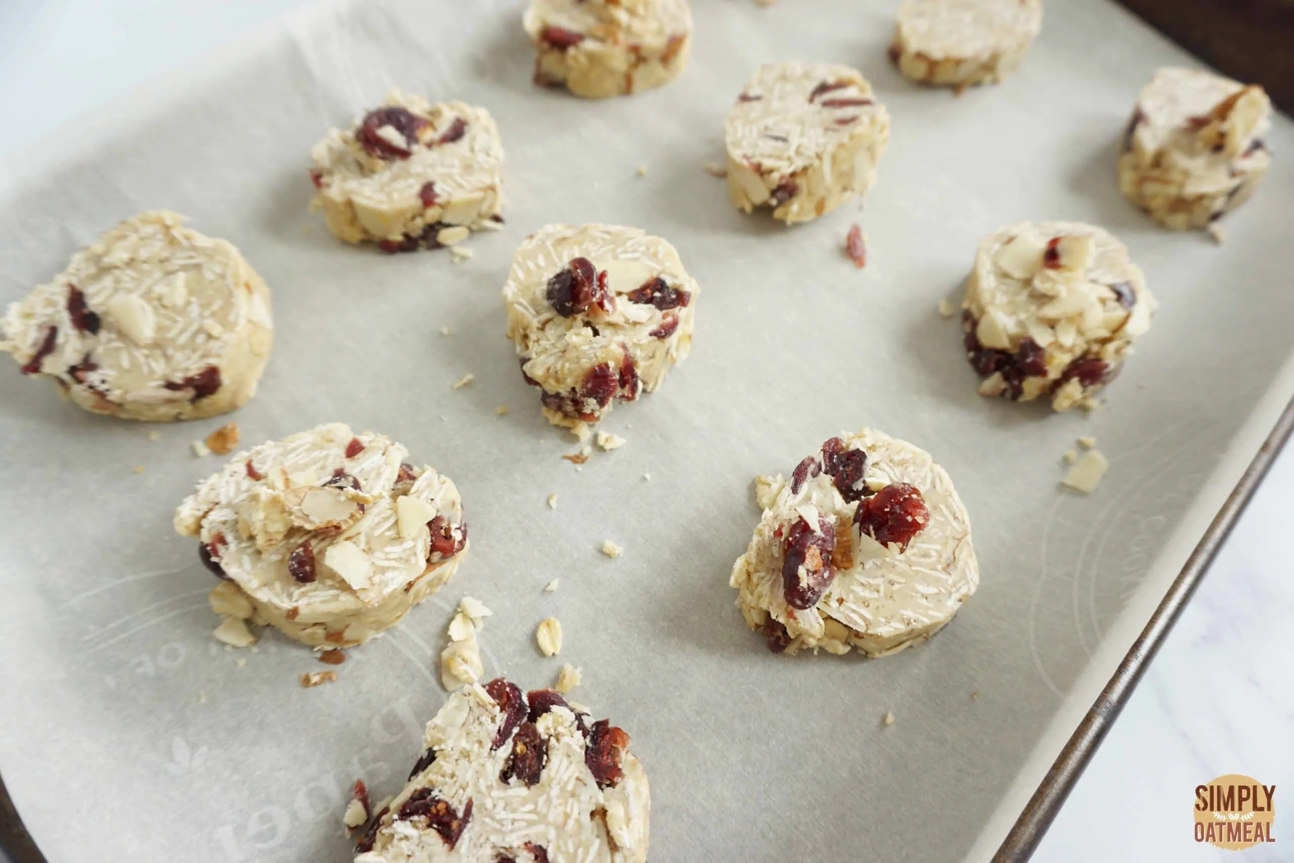 Raw cranberry almond oatmeal cookies on baking sheet.