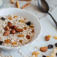 Bowl of oats topped with nuts and dried fruit.