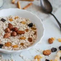 Bowl of oats topped with nuts and dried fruit.