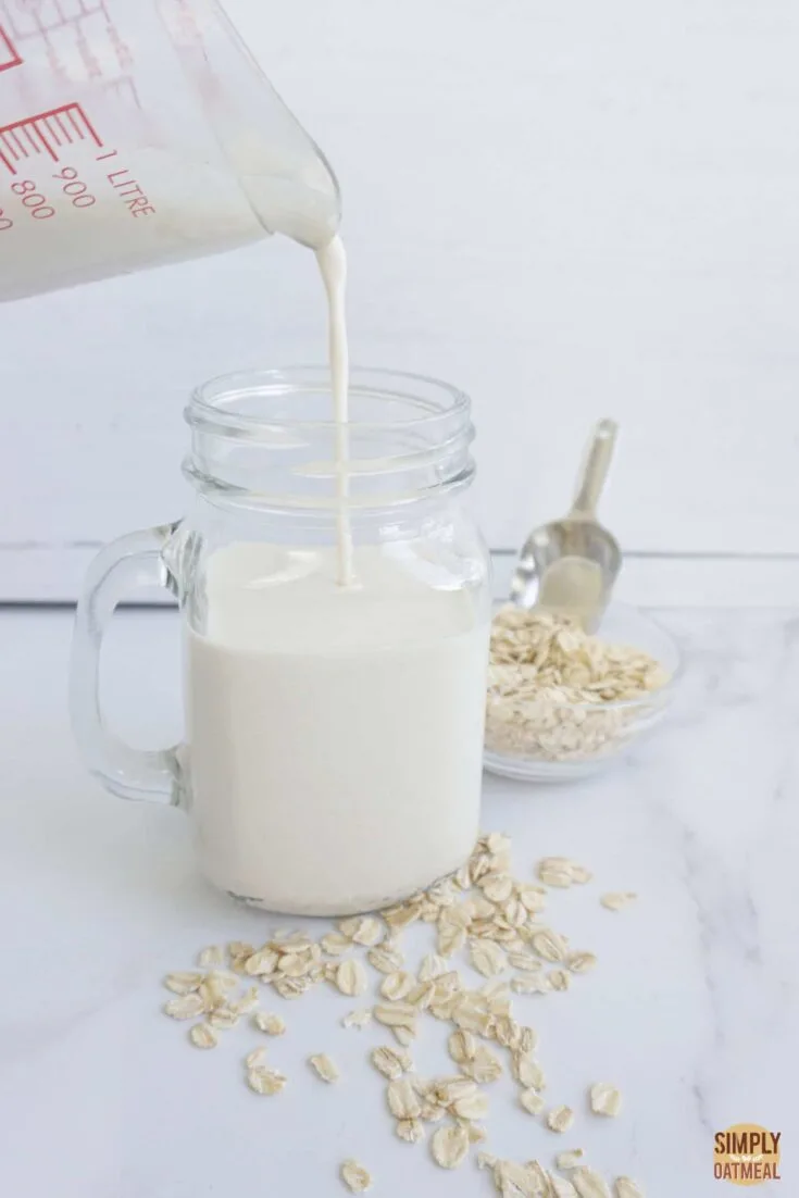 Pouring creamy oat milk without oil into a glass cup