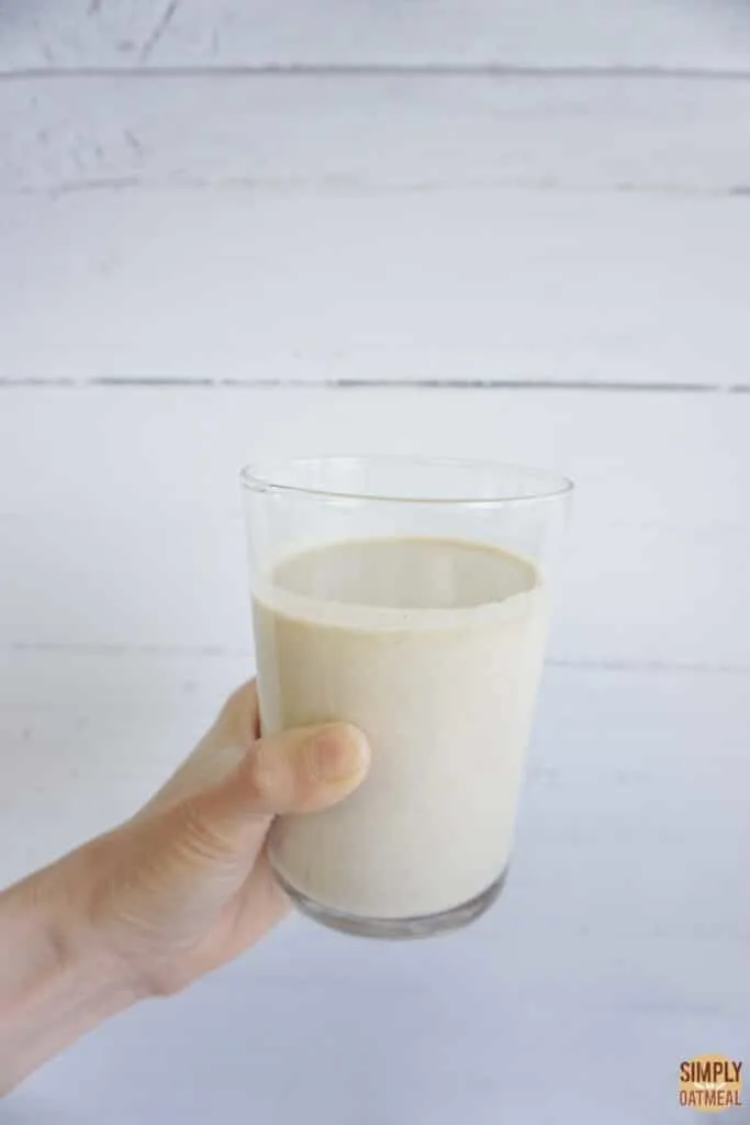 Hand holding a cup of oat milk like oatly